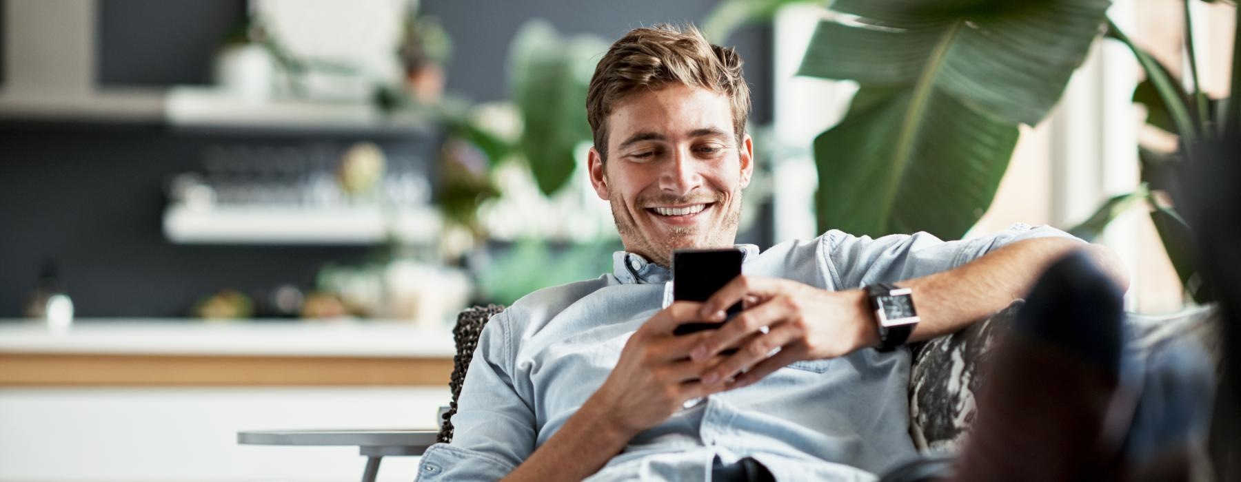 a person laying on a couch and looking at the phone
