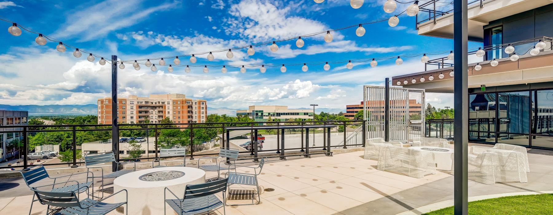 a patio with chairs and tables and a large fire pit